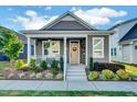 Gray craftsman style home with a white porch and landscaping at 135 Village Walk Dr, Clayton, NC 27527