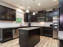 Modern kitchen featuring dark wood cabinets, stainless steel appliances, and an island with granite countertop at 60 Sutherland Dr, Franklinton, NC 27525