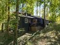 Dark-colored house exterior with a deck, nestled in a wooded setting at 9601 Leslie Dr, Chapel Hill, NC 27516