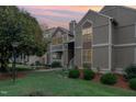 Exterior view of condo building with landscaping and walkway at dusk at 3706 Chimney Ridge Pl # 201, Durham, NC 27713