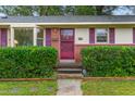 Front entrance of a brick ranch house with a red door and green bushes at 2509 Mckinney St, Burlington, NC 27217