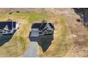 An aerial view of a green two-story home with a black roof and a gravel driveway at 7814 Nc 27, Coats, NC 27521