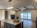 Open floor plan with kitchen island, stone fireplace, and wood-look flooring at 6733 Oscar Barham Rd, Wake Forest, NC 27587