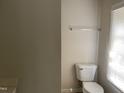 Simple bathroom with toilet, wall-mounted towel rack, and window at 414 E Morehead St, Burlington, NC 27215