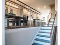 Modern staircase with metal railing overlooking kitchen and dining area at 10420 Sablewood Dr # 115, Raleigh, NC 27617