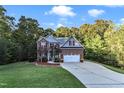 Two story home with brick and gray siding, two car garage, and landscaping at 319 River Knoll Dr, Clayton, NC 27527