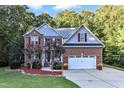 Two story home with brick and gray siding, two car garage, and landscaping at 319 River Knoll Dr, Clayton, NC 27527
