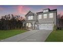 Two-story home with a neutral color scheme, two-car garage, and landscaping at dusk at 23 Eagle Crest Ct # Holly English Country, Lillington, NC 27546