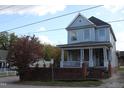 Two-story light blue house with a porch and brick wall, tree with red leaves at 316 E South St, Raleigh, NC 27601