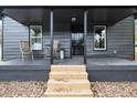 Covered porch with wooden steps and two chairs at 617 Orange Heights Loop Rd, Hillsborough, NC 27278