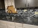 Kitchen with dark granite countertops, gray cabinets, and a decorative backsplash at 206 W Garner Rd, Garner, NC 27529