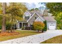 Two-story house with stone and gray siding, a driveway, and mature trees at 204 Harvest Ln, Pittsboro, NC 27312