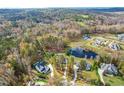 Aerial view of a house and lot in a wooded neighborhood near a pond at 204 Harvest Ln, Pittsboro, NC 27312