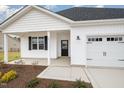 Front view of a charming house with a white exterior, black door, and a two-car garage at 33 Barony Ln, Smithfield, NC 27577