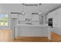 Modern kitchen with white cabinets, large island, and hardwood floors at 5100 Grist Stone Way, Youngsville, NC 27596