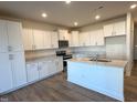 Eat-in kitchen with island, white cabinets, and hardwood floors at 693 Leland Hill Cir, Zebulon, NC 27597