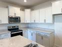 White cabinets, stainless steel appliances, and quartz countertops at 693 Leland Hill Cir, Zebulon, NC 27597