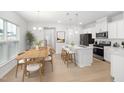 Modern kitchen with white cabinets, island with seating, and dining area at 2840 Huxley Way, Apex, NC 27502