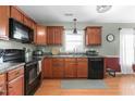 Kitchen with wood cabinets, black appliances, and granite countertops at 102 Redstone Dr, Gibsonville, NC 27249