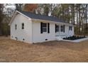 Side view of a white brick ranch house with black shutters and a small porch at 352 Faucette Mill Rd, Hillsborough, NC 27278