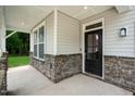 Covered front porch with stone pillars and a dark-colored front door at 8740 Maxine St # 7 Selma, Willow Springs, NC 27592