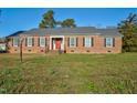 Brick ranch house with red door, landscaping, and a spacious yard at 1204 Breedlove Rd, Nashville, NC 27856