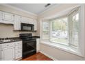 White kitchen cabinets with black appliances at 3116 Coachmans Way, Durham, NC 27705