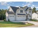Two-story home with gray siding, three-car garage, and landscaped lawn at 323 W Amber Oak Dr, Selma, NC 27576