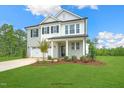 Two-story home with gray brick and white accents, two-car garage, and landscaped yard at 8749 Maxine St # 11 Holly, Willow Springs, NC 27592