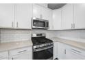 Modern kitchen with white cabinets, stainless steel appliances, and subway tile backsplash at 1005 Kindness Ln, Durham, NC 27703