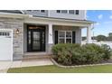 Inviting front entrance with stonework, a black door, and landscaping at 38 Locomotive Way, Clayton, NC 27520