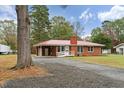 Front view of brick ranch house with red metal roof, landscaped yard, and a long driveway at 604 Central Ave, Butner, NC 27509