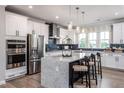 Modern kitchen with large island, stainless steel appliances, and blue backsplash at 1212 Holding Village Way, Wake Forest, NC 27587