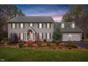 Two-story house with gray siding, brick accents, and a two-car garage, illuminated at dusk at 624 Great Pine Way, Raleigh, NC 27614