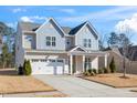 Two-story house with gray and beige siding, white garage door, and landscaping at 78 N Porcenna Ln, Clayton, NC 27527