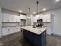 Modern kitchen with white cabinets, dark island, stainless steel appliances, and wood-look flooring at 136 S Mistflower St, Clayton, NC 27520