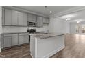 Modern kitchen featuring gray cabinets, granite countertops, stainless steel appliances, and island at 217 Broomgrove Way, Wake Forest, NC 27587