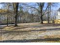 Front view of a property with trees, a gravel driveway, and a wooden fence at 414 Clayton Rd, Durham, NC 27703