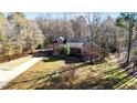 Aerial view of a two-story brick home nestled amidst trees, featuring a driveway and grassy areas at 25 Sylvan Way, Zebulon, NC 27597