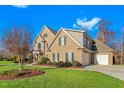 Large brick home with a three-car garage, landscaped yard, and trees at 4109 Cheek Point Pl, Burlington, NC 27215