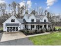 White farmhouse with black accents, a metal roof, and a large porch at 2418 Crossroads Ave, Hillsborough, NC 27278