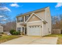 Two-story house with beige vinyl siding, a white garage door, and a landscaped yard at 722 Blue Lake Dr, Mebane, NC 27302