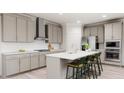 Modern kitchen with gray cabinets, white backsplash, and island with seating at 605 Emerald Bay Cir, Raleigh, NC 27610