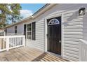 Black front door and white siding with wooden deck at 174 Pine Needles Dr, Lillington, NC 27546