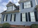 Close-up of blue siding, black shutters and dormers on a two-story house at 7513 Orchard Crest Ct, Apex, NC 27539