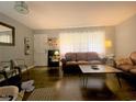 Living room features a brown leather couch and coffee table, hardwood floors, and large windows at 807 W Trinity Ave # 241, Durham, NC 27701