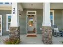 Inviting front entrance with stone columns and a modern front door at 1833 Ballard Rd # Clayton Craftsman, Fuquay Varina, NC 27526