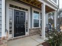 Front porch with black front door, rocking chairs, and brick accents at 817 Heartpine Dr, Mebane, NC 27302
