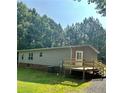 Mobile home with a deck and surrounding trees at 7055 Old Plantation Dr, Graham, NC 27253