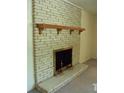 White brick fireplace with a wooden mantel and brass andirons at 1133 Evans Rd, Cary, NC 27513